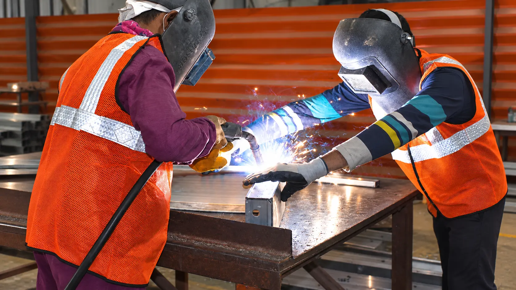 Two Navkaar fabricators in welding masks at work on formwork panels
